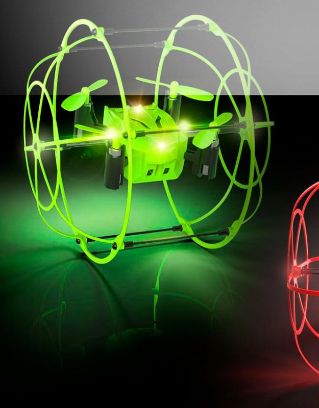 Green mini drone with protective cage and glowing LED lights in flight.