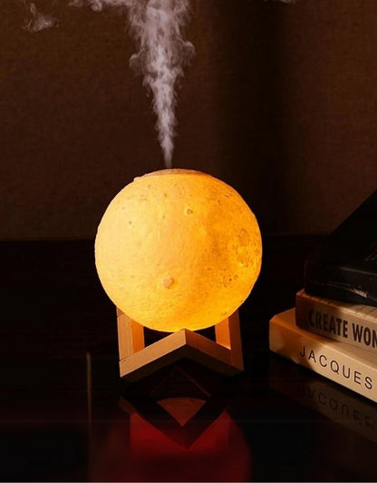 An essential oil diffuser designed to resemble a moon, emitting mist, placed on a wooden stand.