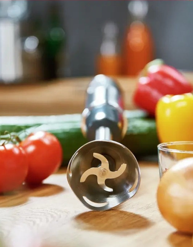 Stainless steel 4-blade head of Moulinex 1000W immersion blender surrounded by fresh vegetables