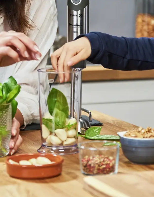 Moulinex QuickChef immersion blender 1000W being used to prepare pesto with basil and garlic
