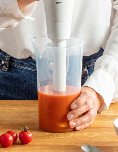 Moulinex hand blender blending fresh tomato sauce in a measuring cup, demonstrating powerful and consistent mixing