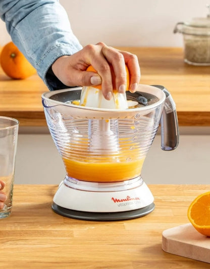 Person manually pressing orange on Moulinex Vita Press Juicer 1 L filled with fresh juice on kitchen counter

