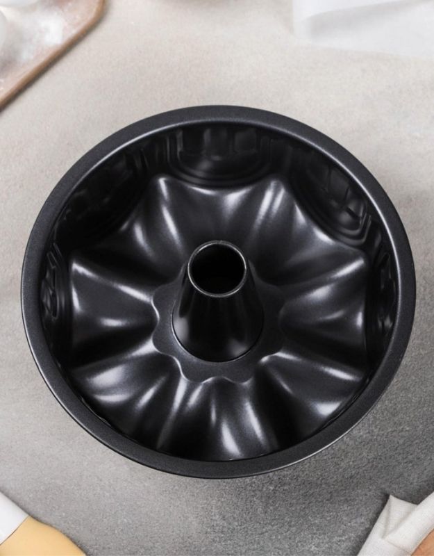 Black Bundt cake pan on a gray surface.  Top view of black nonstick bundt cake pan with central tube.