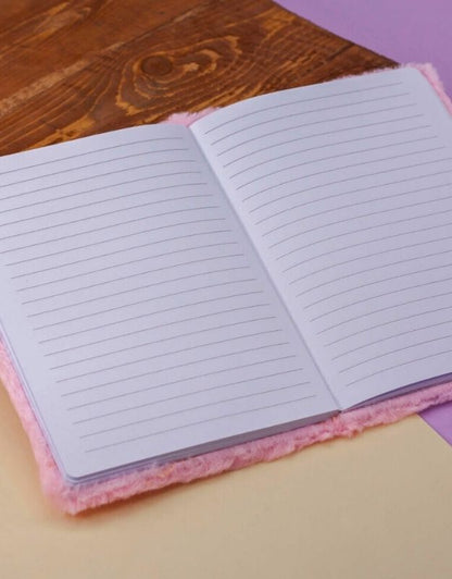Open plush-covered notebook with ruled pages on a wooden and pastel background.