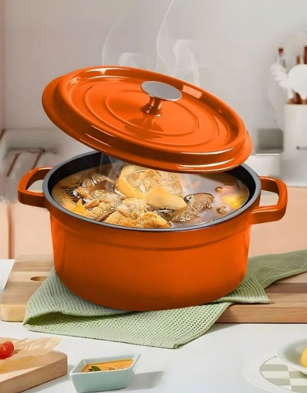 Orange enameled cast iron Dutch oven with a lid on a kitchen counter. Orange enamel cast iron Dutch oven with lid slightly lifted, steaming soup inside.