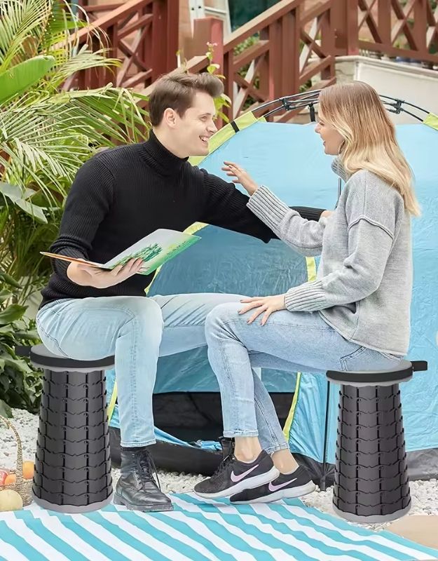 Couple sitting on portable folding stools outside tent.