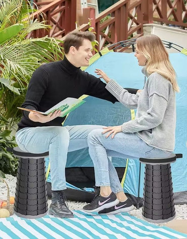 Couple sitting on portable folding stools outside tent.
