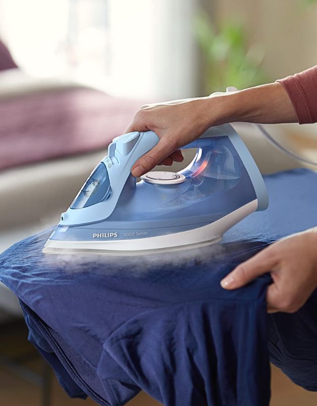 Philips steam iron in use while ironing a blue shirt.