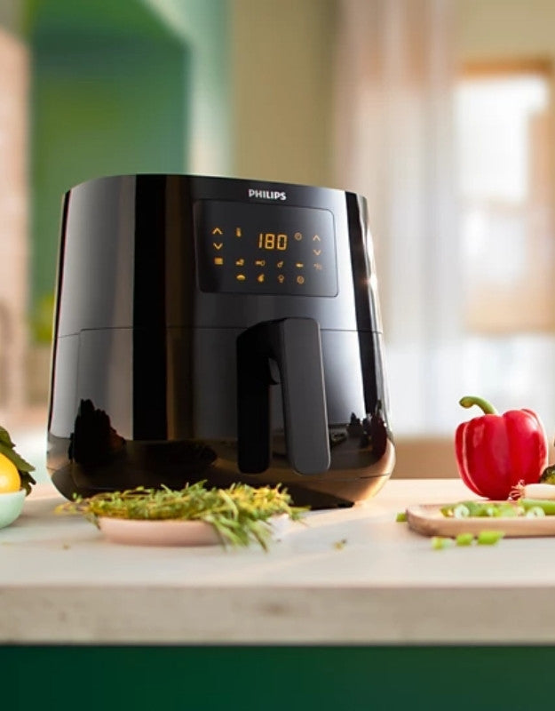 Philips digital airfryer on kitchen counter beside fresh vegetables.