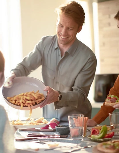 Man serving fries made with Philips airfryer at family meal.