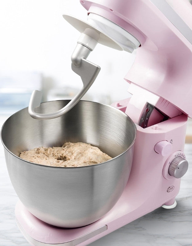 Pink stand mixer with stainless steel bowl and dough hook kneading bread dough.