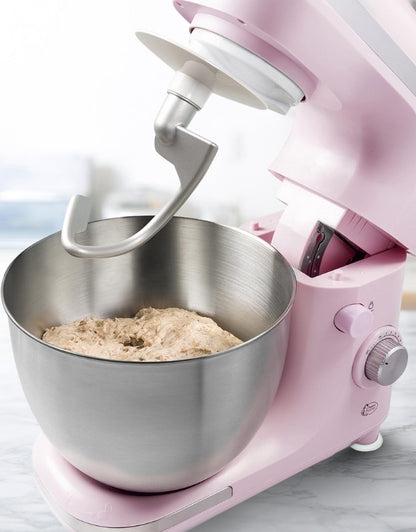 Pink stand mixer with stainless steel bowl and dough hook kneading bread dough.