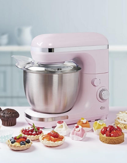 Pink stand mixer with stainless steel bowl surrounded by cakes and pastries.
