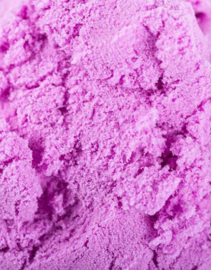 A detailed, close-up shot showing the unique, granular texture of vibrant purple play sand