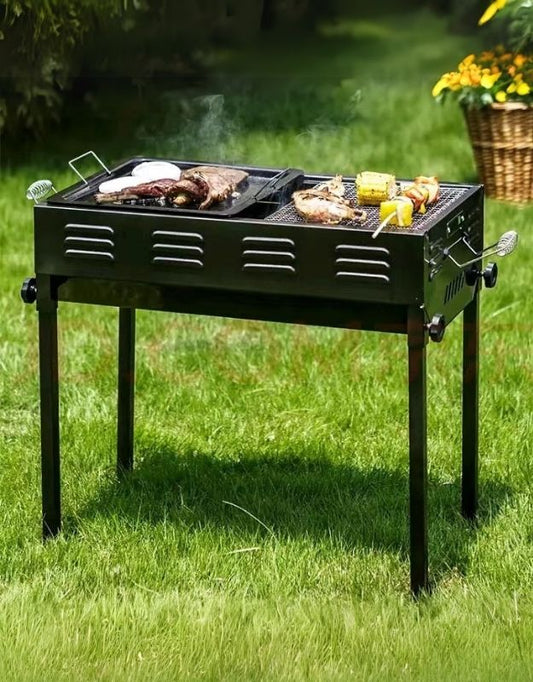 A portable charcoal BBQ grill with food being cooked on it, placed on a grassy outdoor area.