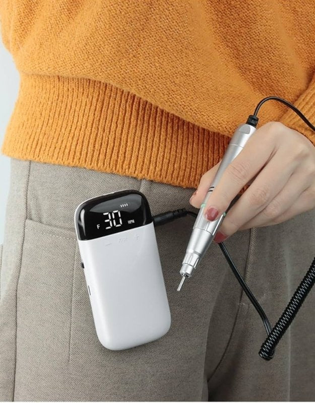 Rechargeable nail drill clipped to pocket for portable use.