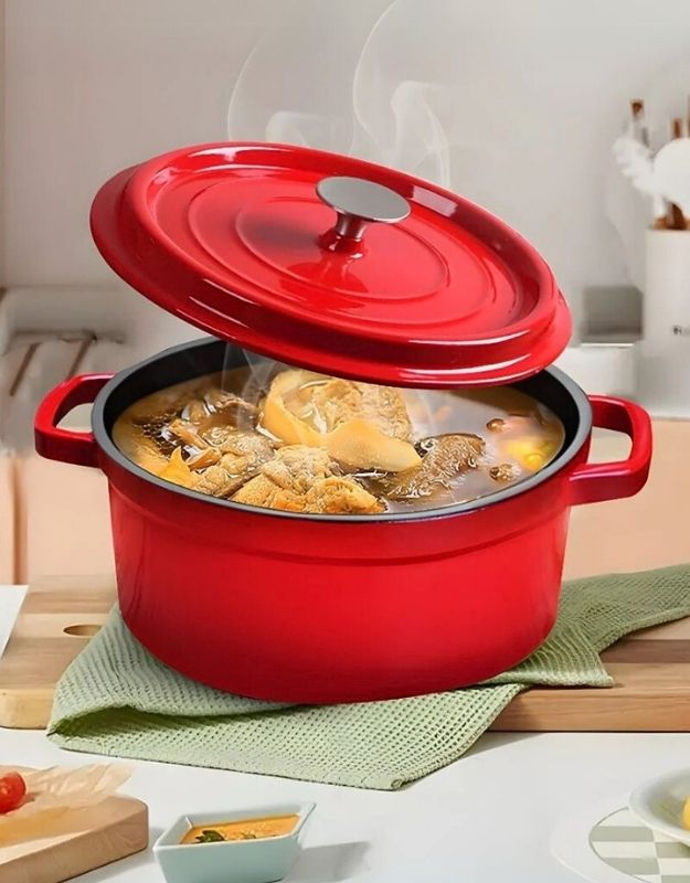 Red enameled cast iron Dutch oven with food inside on a kitchen counter. Red enamel cast iron Dutch oven with lid slightly open, steaming soup inside.