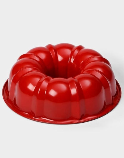Red Bundt cake pan on a white background. Red nonstick Bundt cake pan with fluted design for baking.