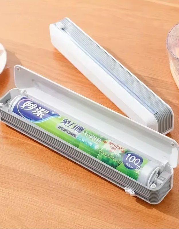 Refillable plastic wrap dispenser open with cling film roll inside.