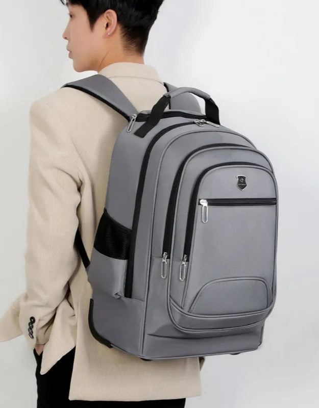 Gray rolling school backpack worn on shoulders by student.
