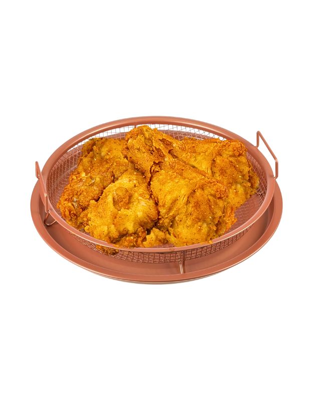 Fried chicken pieces in a round mesh air fryer basket with a nonstick tray.