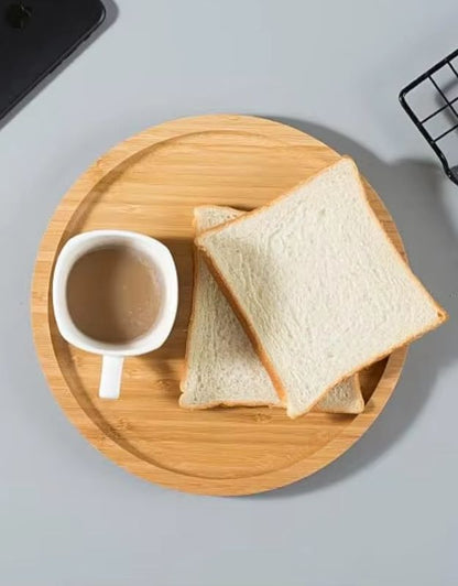 Two slices of white bread on a wooden tray with a cup of coffee. Round bamboo plate holding sliced bread and a cup of coffee for breakfast.