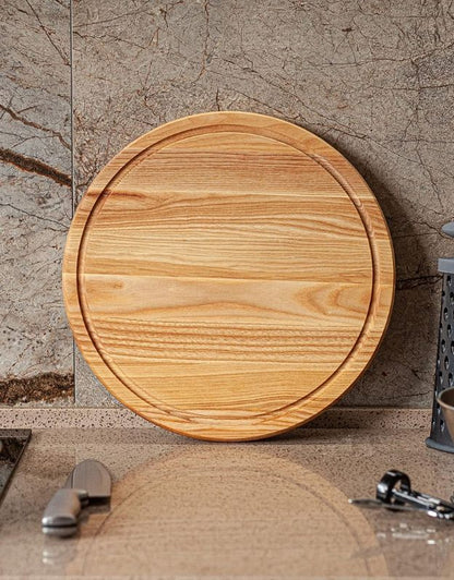 Round wooden cutting board on a marble surface. Empty round wooden chopping board displayed on kitchen counter.