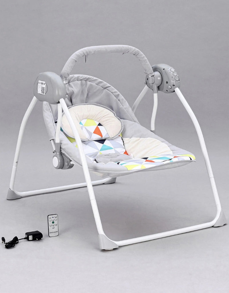 Grey baby bouncer rocking chair with remote control, adapter, and patterned headrest.