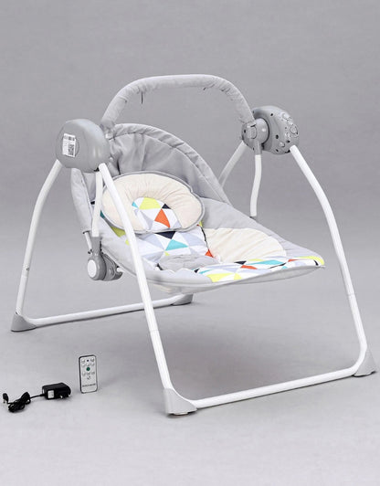 Grey baby bouncer rocking chair with remote control, adapter, and patterned headrest.