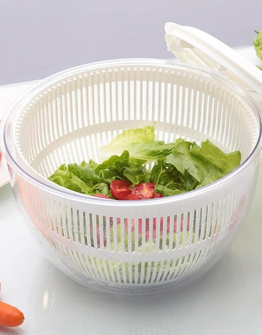 Salad spinner with fresh lettuce and tomatoes inside clear plastic bowl.