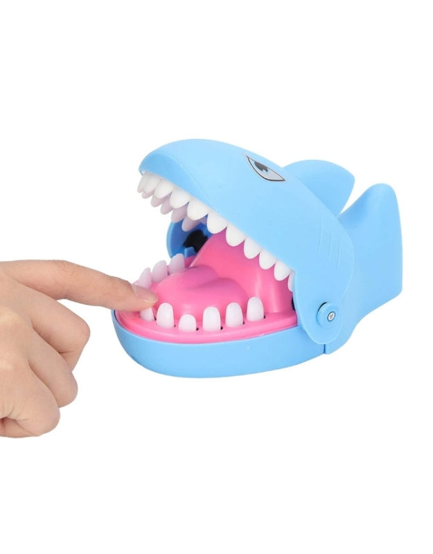The blue "Shark Dentist" game with a finger about to press down on one of its teeth to play the game
