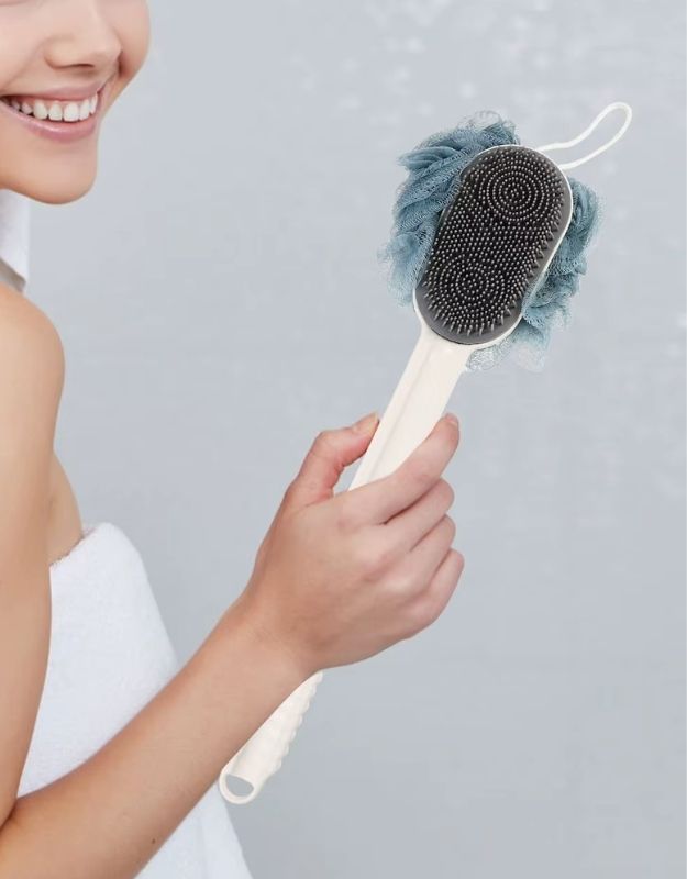 A woman holding a Loofah Sponge Back Scrubber Body Wash Sponge on a grey background