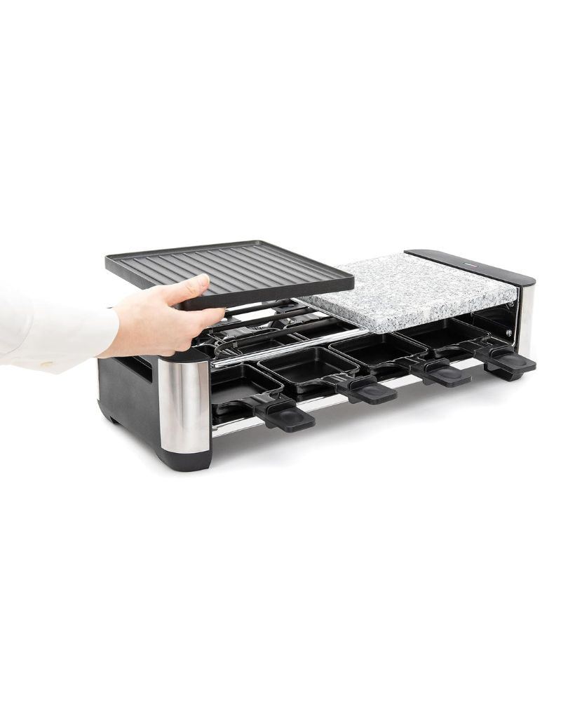 Person placing non-stick grill plate onto Silver Crest 1400W Raclette Grill base with visible stone slab
