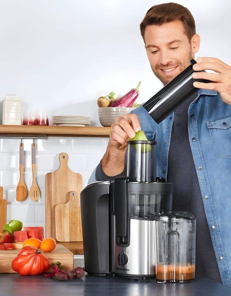 Man using Silver Crest Juicer 800 W to extract juice from fruits in modern kitchen environment
