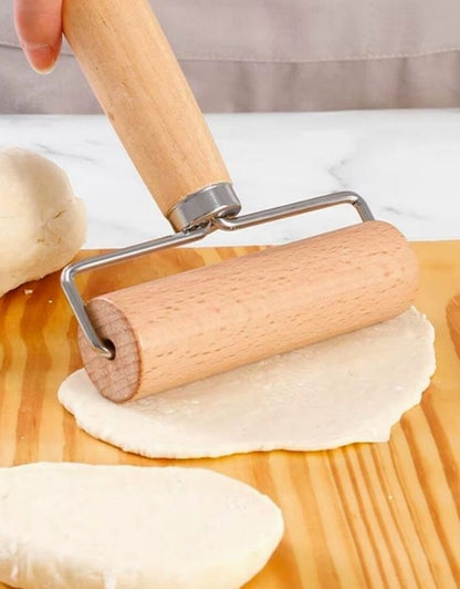 Wooden rolling pin being used on dough on a wooden surface. Wooden dough roller with handle flattening dough on wooden board.