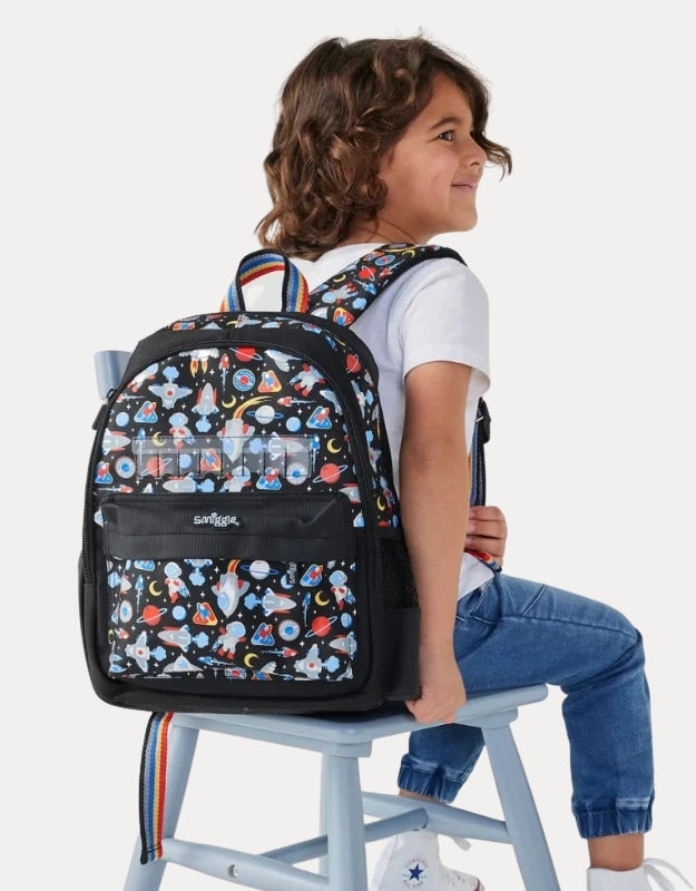 A child sitting while wearing the Smiggle Lets Play backpack.