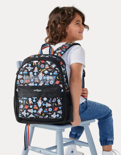 A child sitting while wearing the Smiggle Lets Play backpack.