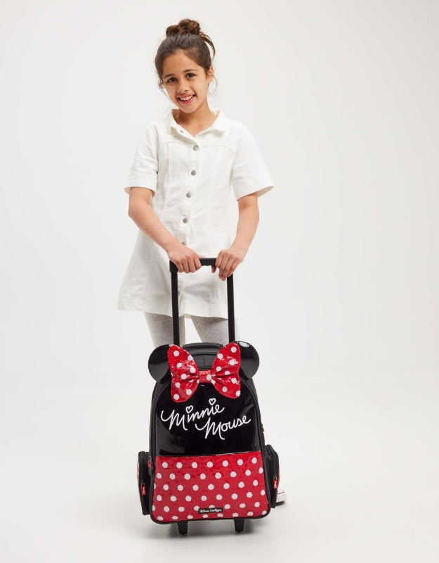 Girl smiling while holding Smiggle Minnie Mouse trolley backpack with light-up wheels.