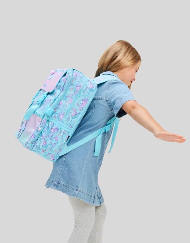 Young girl wearing Smiggle 17.7 inch foldover seahorse school backpack in pastel blue and purple with glitter details