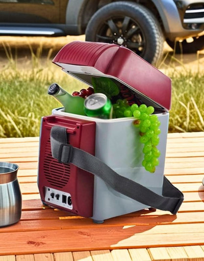 Portable cooler with food and drinks on a wooden table outdoors. Portable mini fridge cooler and warmer with strap, filled with drinks and fruits for outdoor use.