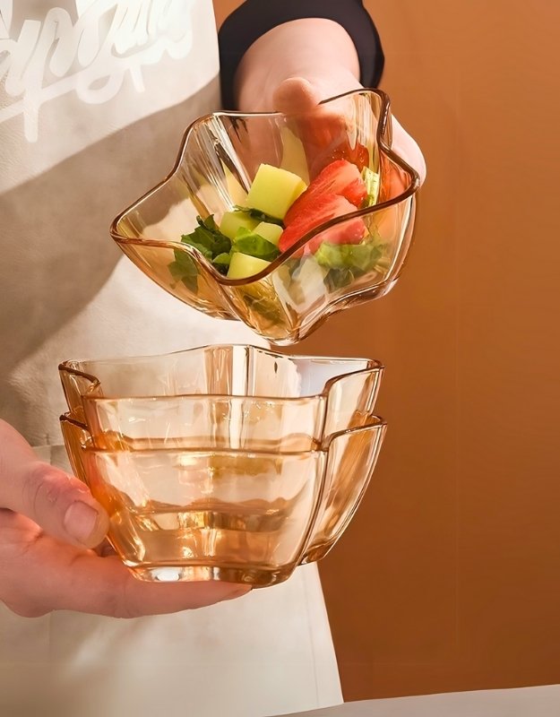 A person holding star-shaped glass bowls, one filled with salad