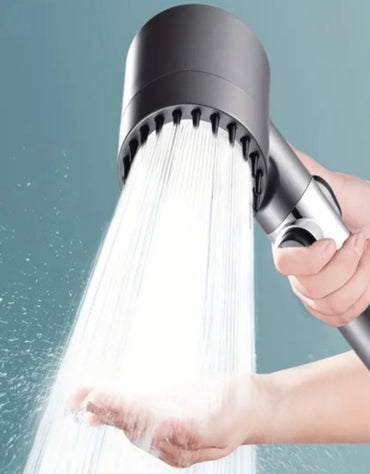 Shower head with water flowing against a neutral background. Filtered shower head with strong water flow demonstrated on hand.