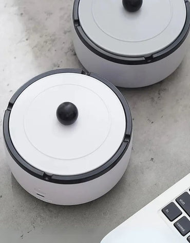 Portable rechargeable smokeless ashtray with modern design on desk.
