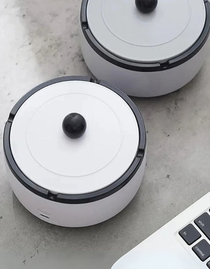 Portable rechargeable smokeless ashtray with modern design on desk.